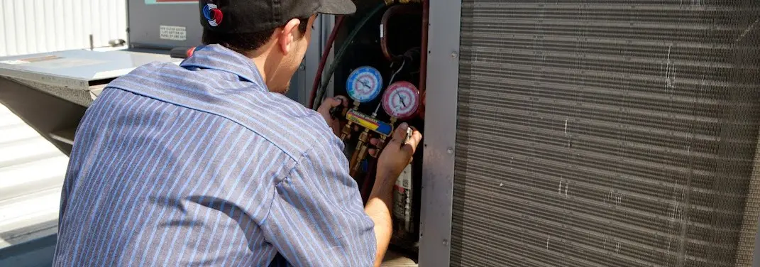HVAC technician servicing a condenser unit in North East